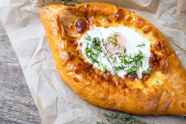 Khachapuri avec l'oeuf et les herbes. Cuisine géorgienne.