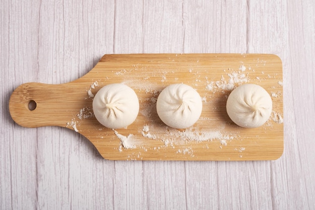 Khinkali cru sur une planche de bois sur fond blanc