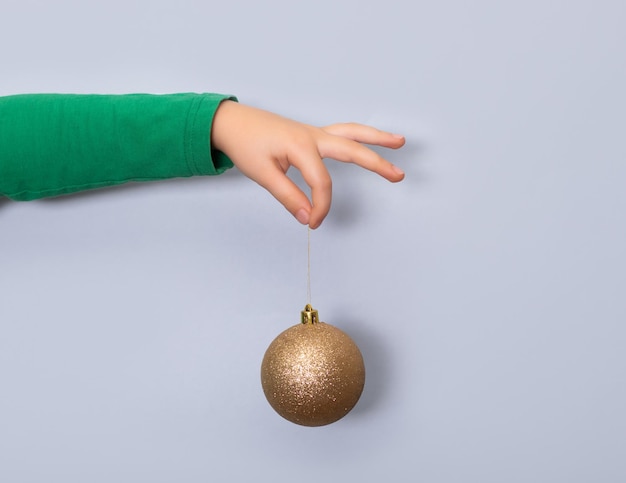 Kid bambin fille tient un jouet de boule d'arbre de Noël doré sur fond bleu Copiez l'espace pour la conception ou le texte Modèle de maquette de bannière Nouvel An