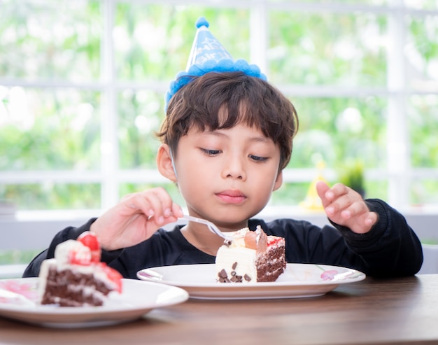 Kid avec un chapeau de fête mange un gâteau d&#39;anniversaire