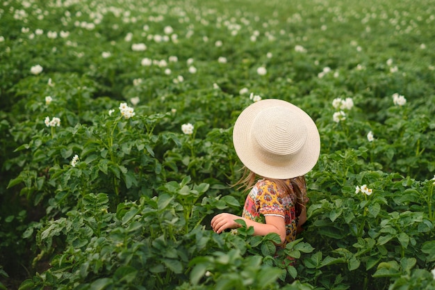 Kid En Chapeau De Paille Tissé Dans Le Domaine De La Culture Des Pommes De Terre