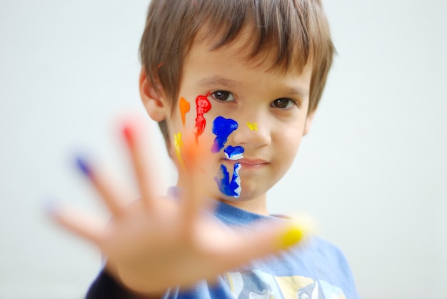 Kid avec de la couleur sur ses doigts et son visage