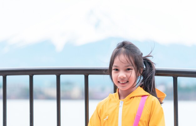 Kid est debout devant le lac Kawaguchiko et le mont Fuji en hiver.