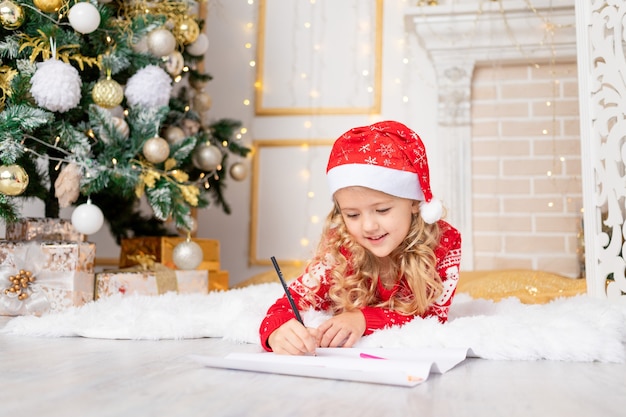 Kid fille écrit une lettre au père Noël à l'arbre de Noël