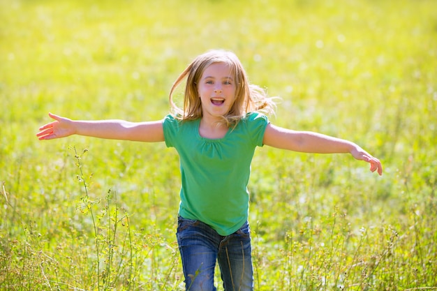 kid fille heureuse en cours d&#39;exécution ouvert les mains en vert en plein air