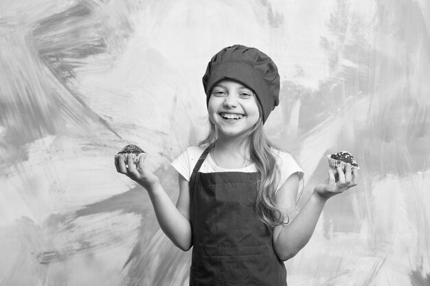 Photo kid fille heureuse cuisiner en tablier de toque rouge