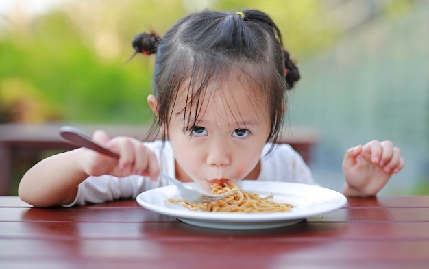 Kid fille mangeant des nouilles japonaises yakisoba sur la table