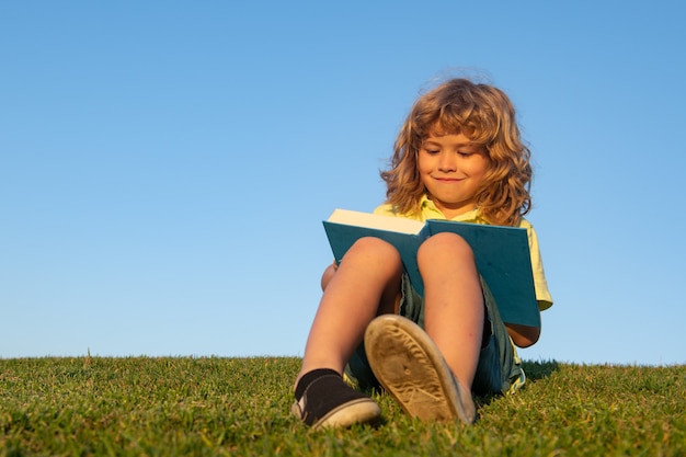 Kid garçon a lu un livre dans le parc.