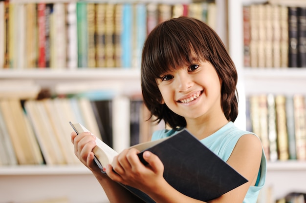 Kid avec livre dans la bibliothèque