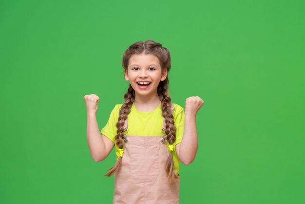 Kid montre ses poings. Une fille joyeuse sur fond vert isolé.