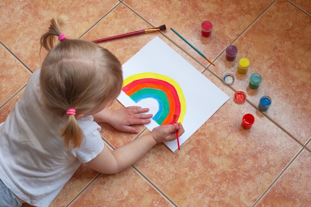 Kid peinture arc-en-ciel à la maison pendant la quarantaine du coronavirus pandémique.