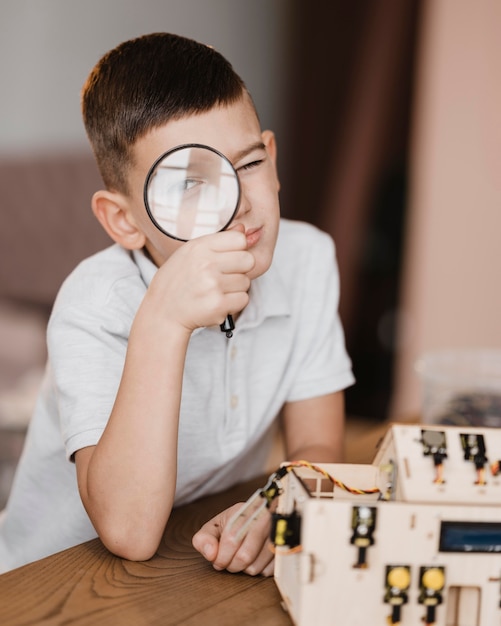 Kid regardant un objet en bois électrique avec une loupe