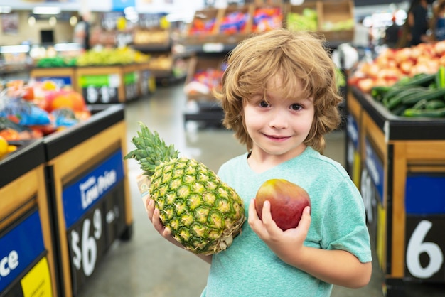 Kid tenir l'ananas au supermarché. Concept de vente, de consommation et d'enfants.