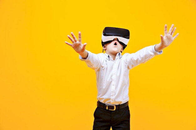 Kid en tenue formelle portant des lunettes VR mettant les mains dans l'excitation isolée