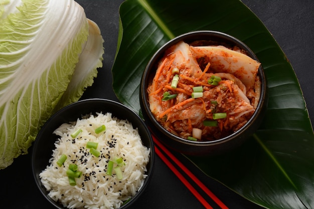 Kimchi et riz dans un bol noir avec des baguettes Cuisine coréenne