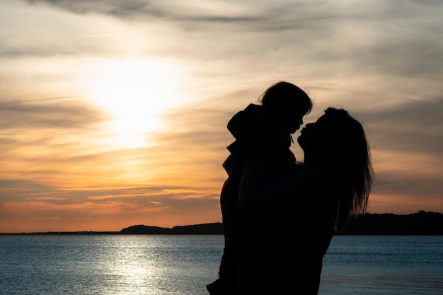 Kinde mit Mutter unter Sonnenuntergang im Urlaub