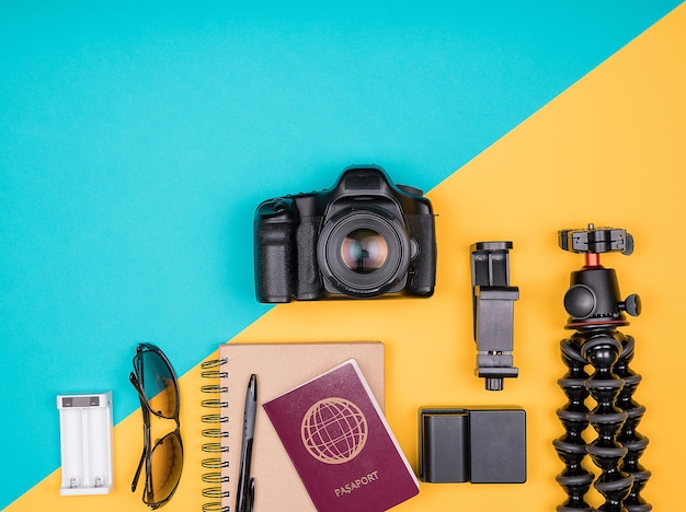 Kit de blogueur voyageur pour les vacances d'été. Vue de dessus. Mise à plat. Appareil photo avec accessoires à côté de lunettes de soleil, carnet papier et passeport