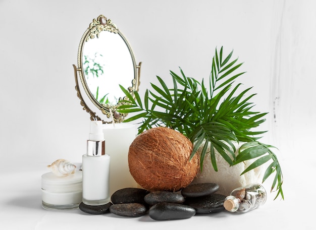 Photo kit spa avec produits cosmétiques à la noix de coco, pierres zen, miroir, feuilles de palmier et coquillages. concept pour spa, salon de beauté et de santé, magasin de cosmétiques. gros plan photo sur fond blanc