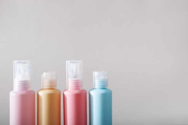 Kit de voyage. Ensemble de quatre bouteilles en plastique pour produits cosmétiques. Fond gris