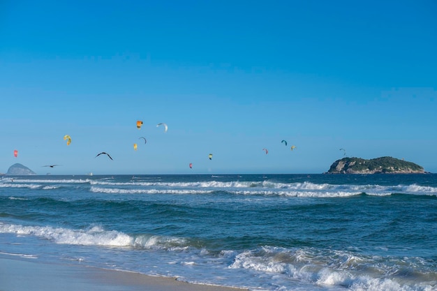 Kiteboarders et oiseaux contre le ciel bleu sur la plage de Rio de Janeiro Brésil Océan et ciel