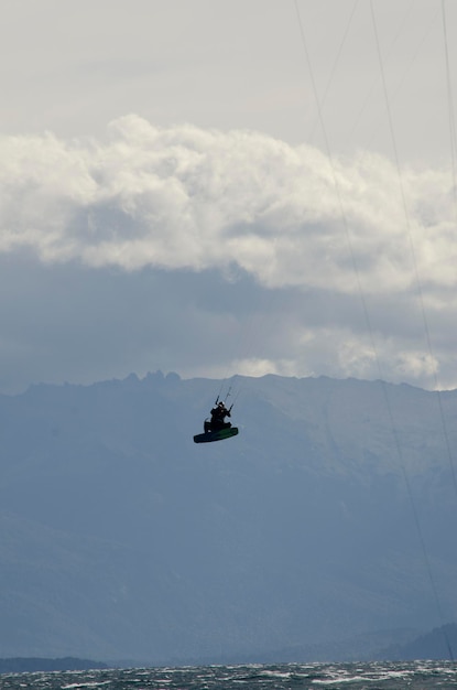 Kitesurf sportif sautant kitesurf sur un lac avec des montagnes en arrière-plan