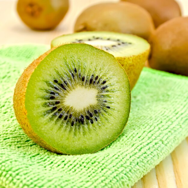 Kiwi entier et demi, serviette verte sur une planche en bois