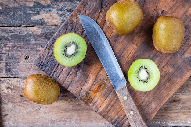 Kiwi frais coupés en deux sur une planche à découper en bois.