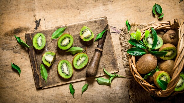 Kiwi frais en tranches avec un couteau et un panier plein et des feuilles