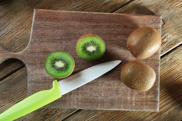 Kiwi juteux avec un couteau sur une planche à découper sur fond de bois