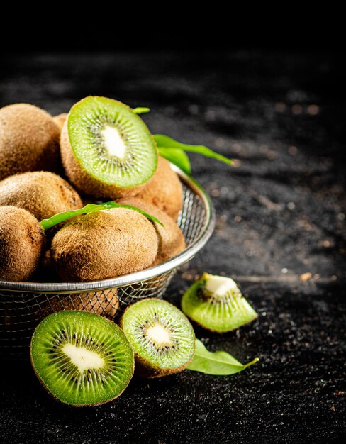 Photo kiwi mûr avec des feuilles dans une passoire sur la table