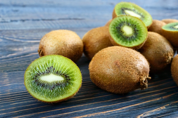 Kiwi mûr frais sur une table en bois. Fruits entiers et demi-coupés. Fruit exotique. La nourriture saine.