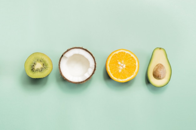 Kiwi, noix de coco, orange et avocat sur mur vert