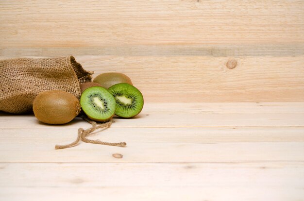 Kiwi et un sac de toile de jute sur un fond en bois et un espace de copie