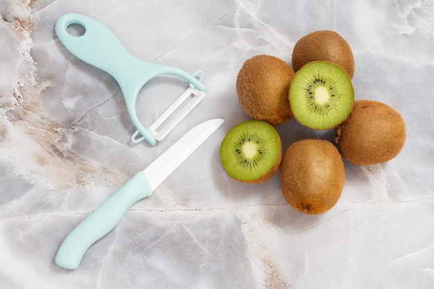 Kiwis entiers et tranchés et couverts posés sur la table de la cuisine.