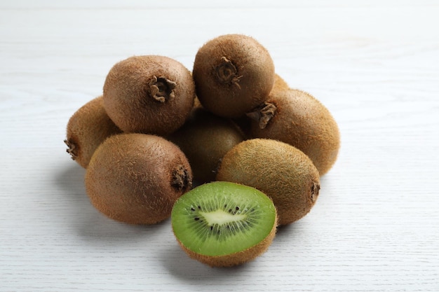 Kiwis frais coupés et entiers sur une table en bois blanche