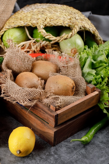 Kiwis à l'intérieur d'un panier et d'un plateau en bois.