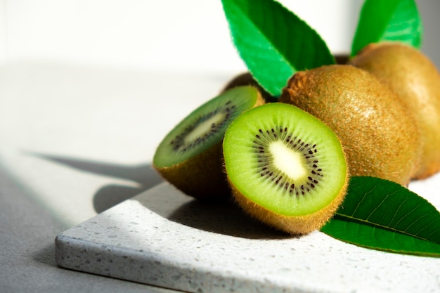 Kiwis mûrs au soleil Tas de kiwis entiers avec des feuilles vertes et des kiwis fraîchement coupés sur la table Fruits biologiques sains pleins de vitamines et d'antioxydants