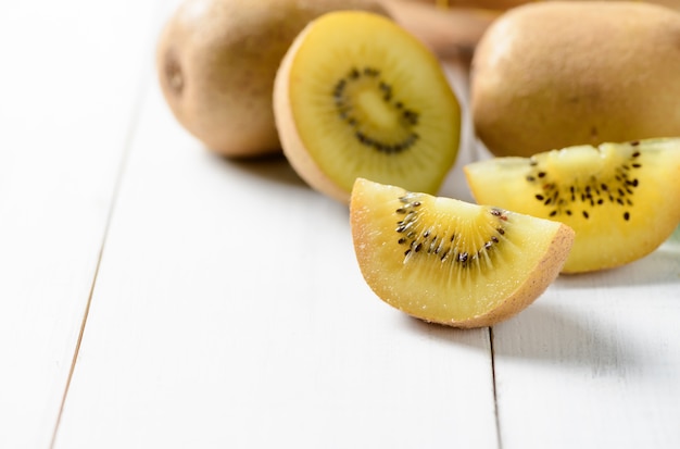 kiwis en tranches jaunes ou or sur fond de bois blanc, fruits sains