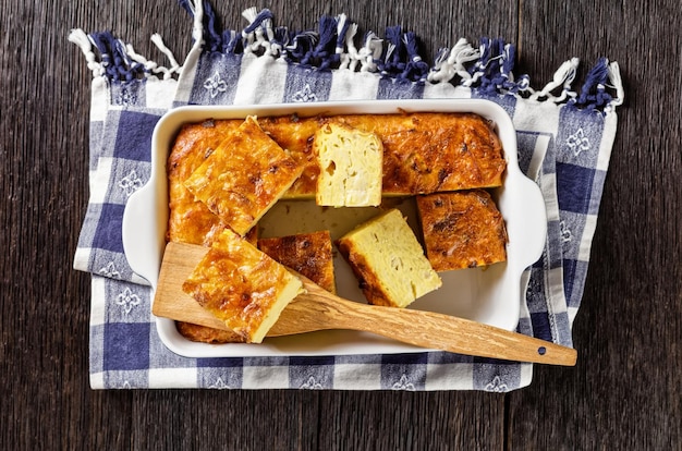 Kugel de pommes de terre cuit au four ou casserole de pommes de terre râpées coupées en portions dans un plat allant au four sur une table en bois recette de vacances juives