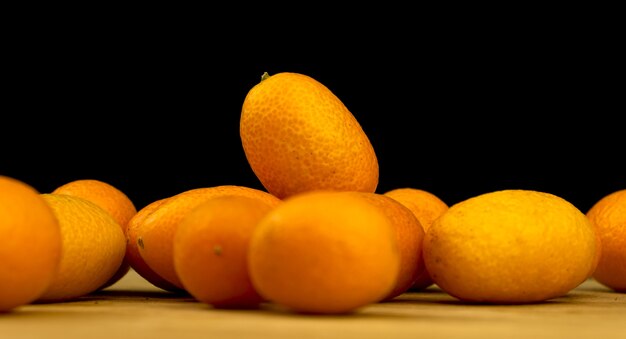 Kumquat, agrumes frais sur une planche de bois sur fond noir. Cumquat, alimentation saine, concept de régime cru. Copier la photo de l'espace