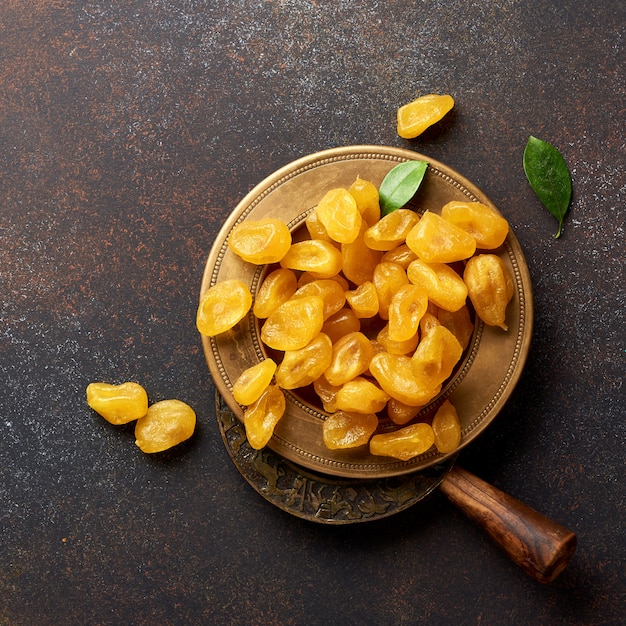 Photo kumquat jaune séché avec des feuilles vertes sur fond marron. vue de dessus.