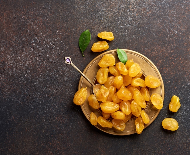 Photo kumquat jaune séché avec des feuilles vertes sur une surface brune. vue de dessus.