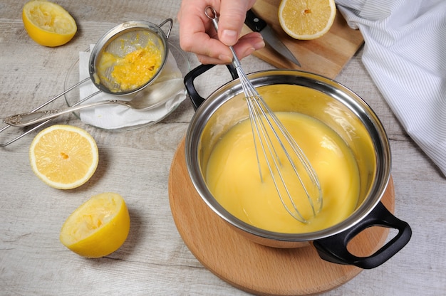 Kurd au citron fraîchement préparé - crème anglaise sur jus de fruits, dans une casserole fouettée au fouet