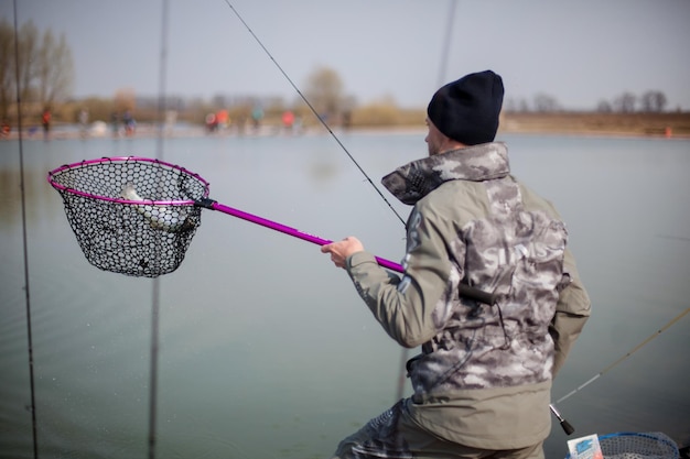 Kyiv, Ukraine, le 16 avril 2018. Un pêcheur avec une canne à lancer, tient un poisson dans une épuisette.