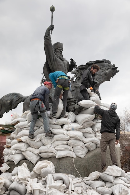 KYIV UKRAINE 26 mars 2022 Monument à Hetman Sahaidachny avec des sacs de sable pour se protéger contre les bombardements russes à Kiev Un groupe de jeunes couvre le monument avec des sacs de sable