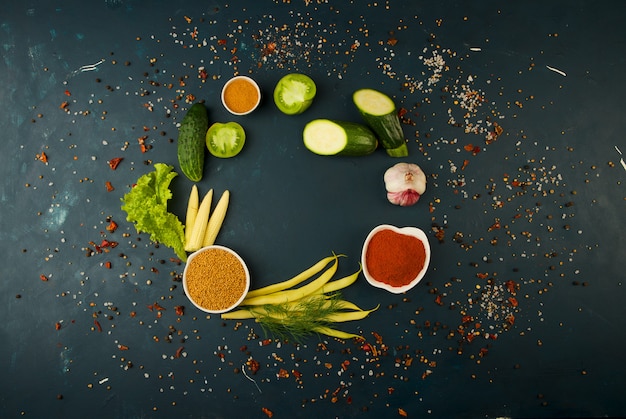 LÉGUMES FRAIS SUR UN FONCÉ. LE CONCEPT DE MILLESIME. LES ÉPICES DU CONCOMBRE DE TOMATES VERTES JUS D'ASPERGES DE MAÏS SUR UNE SURFACE FONCÉE.