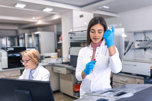 Laboratoire de recherche médicale moderne Femme scientifique travaillant avec une micro-pipette à l'aide d'une tablette numérique pour l'analyse d'échantillons de test Laboratoire scientifique avancé pour le développement de la biotechnologie médicale