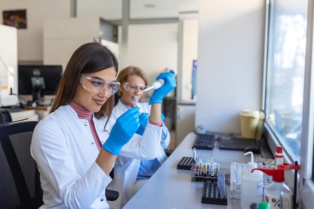 Laboratoire de recherche médicale Portrait d'une belle femme scientifique utilisant une micro-pipette pour l'analyse Laboratoire scientifique avancé pour la médecine Biotechnologie Microbiologie Développement Mains Gros plan