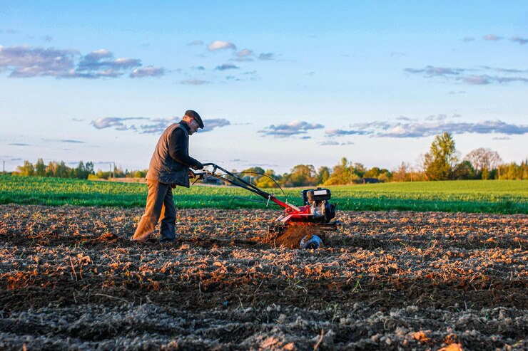 Photo labourer un champ avec un tracteur à conducteur marchant dans une ferme