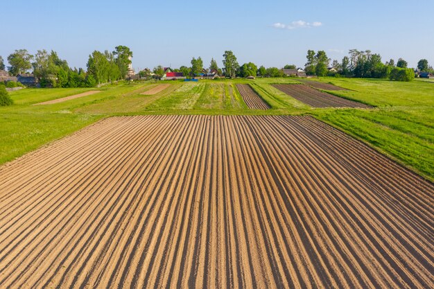 Labourer des sillons pour planter des plantes agronomiques dans la campagne des herbes et des prairies, vue aérienne d'en haut.